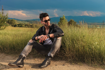 seated man wearing leather jacket looks away to side