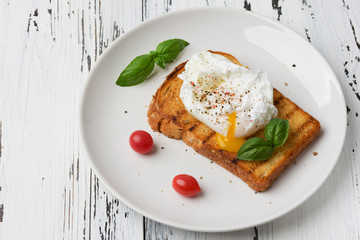 Poached egg on a piece of bread on the wooden table