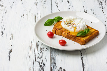 Poached egg on a piece of bread on the wooden table