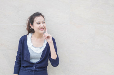 Closeup asian woman look at space with smile face on marble stone wall textured background with copy space