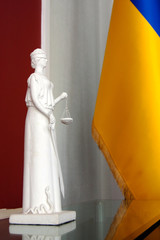 white femida statue on background ukrainian flag