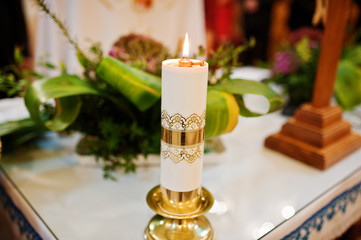 Close-up photo of a candle burning in the church during the wedding ceremony.