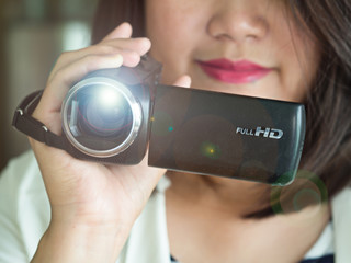 Close up of woman hand holding video camera or camcorder recording or taking events or medias with...