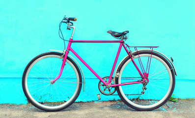 Fototapeta na wymiar Retro old pink bicycle stands on a colorful blue background