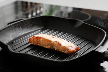 Grill frying pan with slice of salmon on induction stove