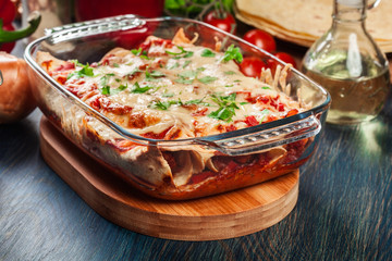Traditional mexican enchiladas with chicken meat, spicy tomato sauce and cheese in heat resistant dish
