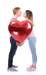 Young couple with heart shaped balloon on white background