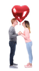 Young couple with heart shaped balloon on white background