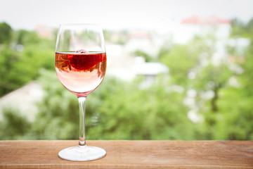 Glass of delicious strawberry wine on blurred background