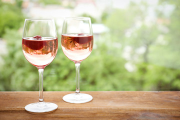Glasses of delicious strawberry wine on blurred background