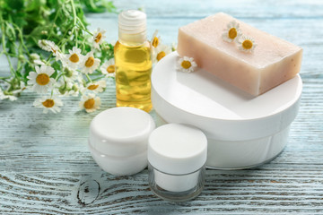 Chamomile cosmetic products with fresh flowers on wooden table