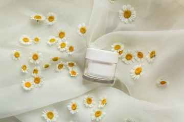 Obraz na płótnie Canvas Chamomile cosmetic product with fresh flowers on fabric background