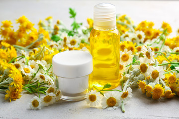 Chamomile cosmetic products with fresh flowers on light background