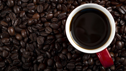 Morning joe, caffeine fix  and coffee time concept with a cup of coffe on roasted coffee beans with copy space