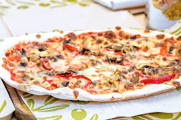 Big vegetables pizza on wooden plate, mushrooms and red pepper with cheese