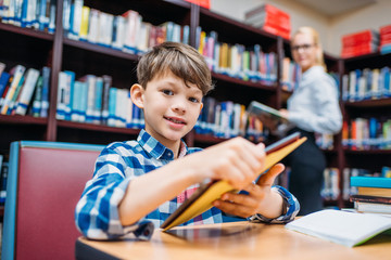 schoolboy holding tablet in library