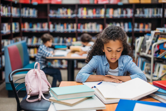 schoolgirl reading book in library - Powered by Adobe