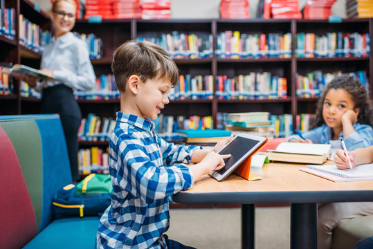 schoolboy using tablet at library - Powered by Adobe