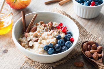 Oatmeal porridge with blueberries, almonds, cinnamon, honey, linseeds and red currants in bowl. Super food for healthy nutritious breakfast