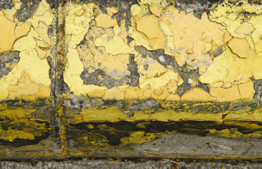 A curb on the side of the road, with pealing yellow paint on it