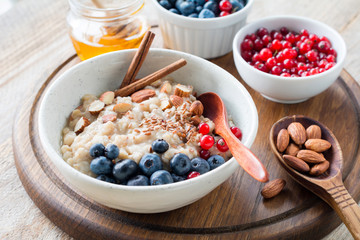 Oatmeal porridge with blueberries, almonds, cinnamon, honey, linseeds and red currants in bowl. Super food for healthy nutritious breakfast