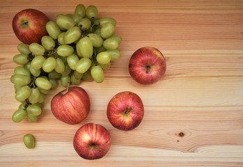 Bunch of grapes and red apples on the wooden table.