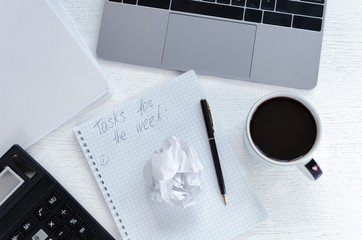 Business workplace with a notebook, a calculator and a notebook with a working plan for a week, cup coffee. Open diary with the inscription: Tasks for the week.