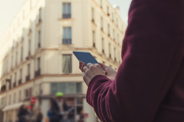 Girl holding cellphone in urban surroundings - shallow depth of field.