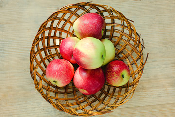 Juicy fresh apples in a basket on a wooden background