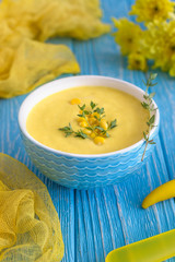 Homemade corn cream soup with thyme and pepper chili on a wooden background