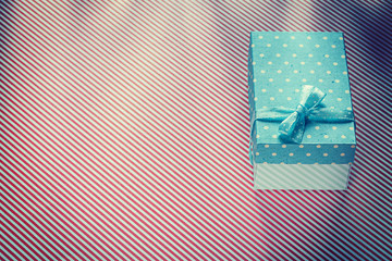 Obraz premium Wrapped present box on red striped textile celebrations concept