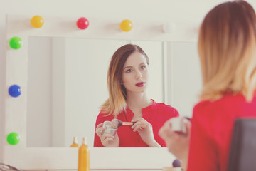 Young caucasian woman applying cosmetics