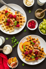 Homemade Belgian waffles with peach, raspberry, fig and honey on brown wooden background. Selective focus