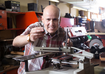 mature worker making mailbox plate on machine
