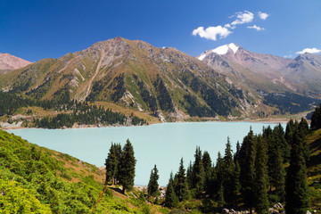Fototapeta na wymiar Big Almaty lake. View of a lake in the mountains. Snow-capped peak in the background. Sunny summer afternoon.
