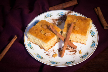 raisin cake decorated with cinnamon on satin on wood table