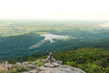 Young man enjoying a valley view from top of a mountain.