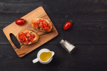 Preparing delicious Italian tomato bruschetta with chopped vegetables, herbs and oil