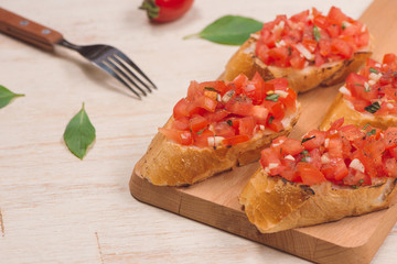 Italian bruschetta with roasted tomatoes, mozzarella cheese and herbs on a cutting board