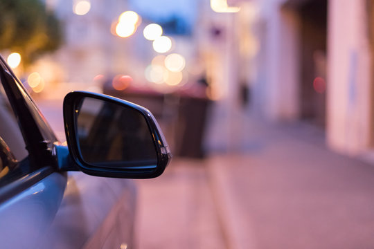 R&uuml;ckspiegel eines parkenden Autos am Abend, Stra&szlig;e