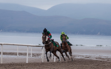 Fototapeta na wymiar Race horses and jockeys competing on the beach