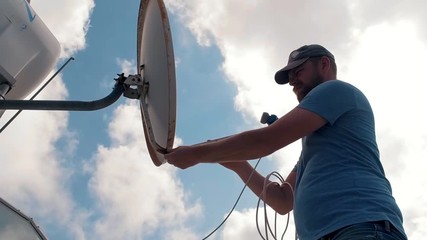 Bearded repairman doing maintenance satellite antenna. Fix cable satellite dish