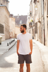 Hipster handsome male model with beard wearing white blank t-shirt with space for your logo or design in casual urban style