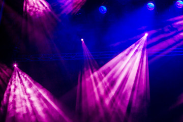 Blue and purple rays from the spotlight through the smoke at the theater or concert hall. Lighting equipment for a performance or show.