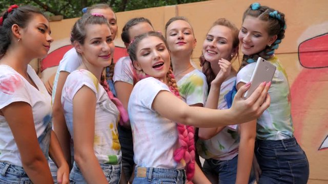 stylish girls make selfi photo on mobile, girlfriends with trendy braids with kanekalon do selfie on gadget, adolescents with bright hair make pictures on android at background of graffiti