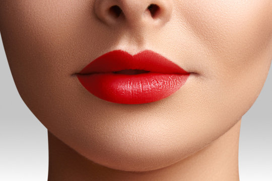 Cosmetics, makeup. Bright lipstick on lips. Closeup of beautiful female mouth with red lip makeup. Clean skin model