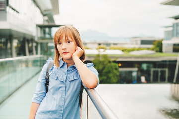 Outdoor portrait of pretty little preteen 10-11 year old girl wearing blue formal dress and backpack