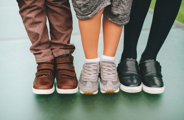 Fashion shoes on kids. Three pairs of children's feet wearing comfortable and fashion trainers. Back to school concept - obrazy, fototapety, plakaty