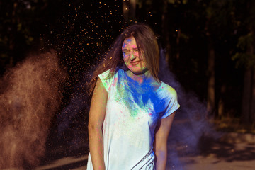 Fototapeta premium Smiling brunette model with long hair covered with colorful Holi powder