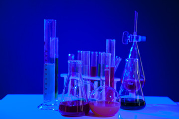 Colored liquid in chemistry set on a table over blue background. Glassware and biology equipment